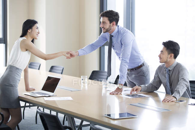Negócios apertando as mãos na sala de reuniões — Fotografia de Stock