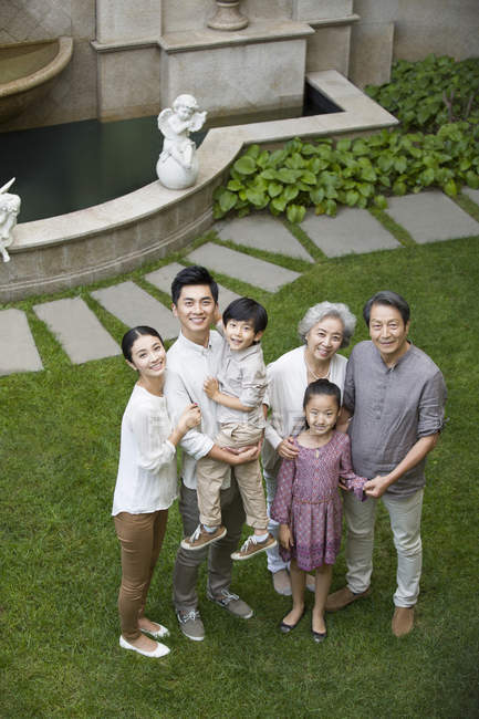 Vista de ángulo alto de la familia china mirando hacia arriba en el césped verde - foto de stock