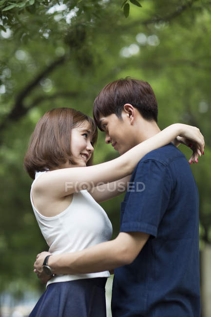 Молодая китайская пара обнимается в парке — стоковое фото
