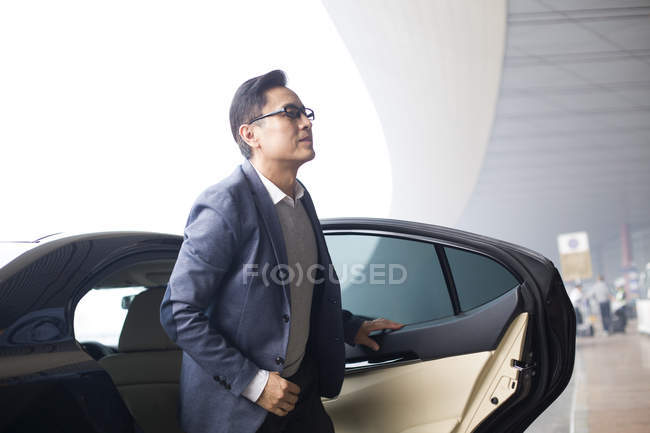 Asiatischer Geschäftsmann steigt im Flughafen-Terminal aus Auto — Stockfoto
