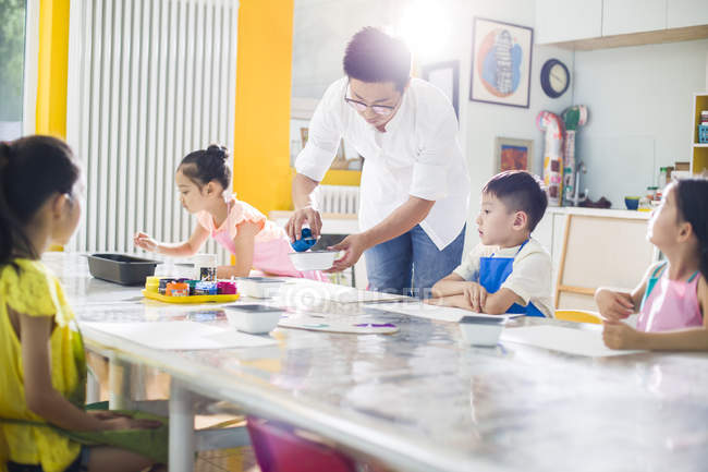 Crianças chinesas pintando em aula de arte com professor — Fotografia de Stock