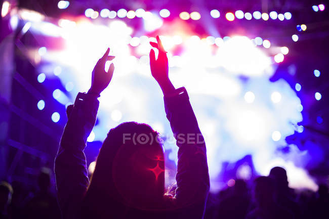 Silhueta feminina com braços levantados no concerto de música — Fotografia de Stock
