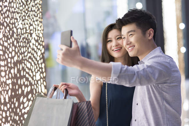 Casal chinês tomando selfie enquanto faz compras — Fotografia de Stock