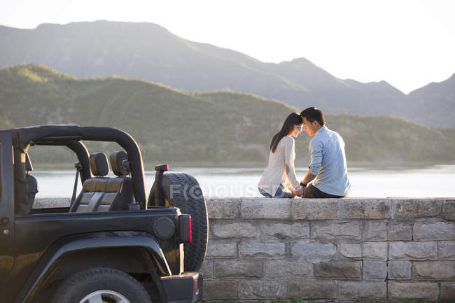 Chinese couple sitting head to head on lakeside in suburbs — Stock Photo