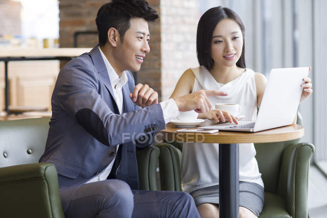 Asian man and woman working with laptop in cafe — Stock Photo