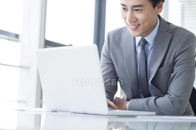 Chinesischer Geschäftsmann mit Laptop im Büro — Stockfoto