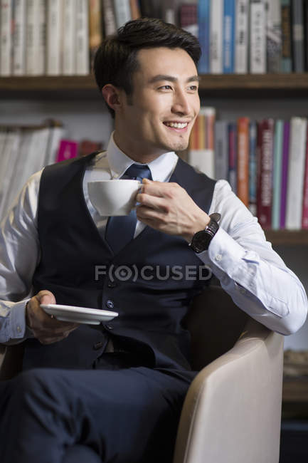 Asian businessman drinking coffee in study — Stock Photo