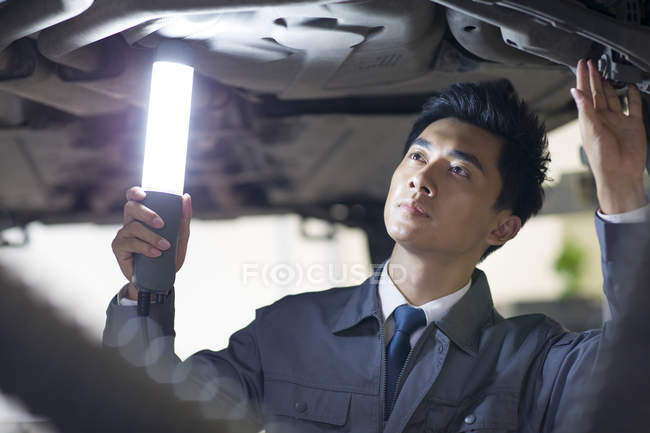 Chinese auto mechanic examining car — Stock Photo