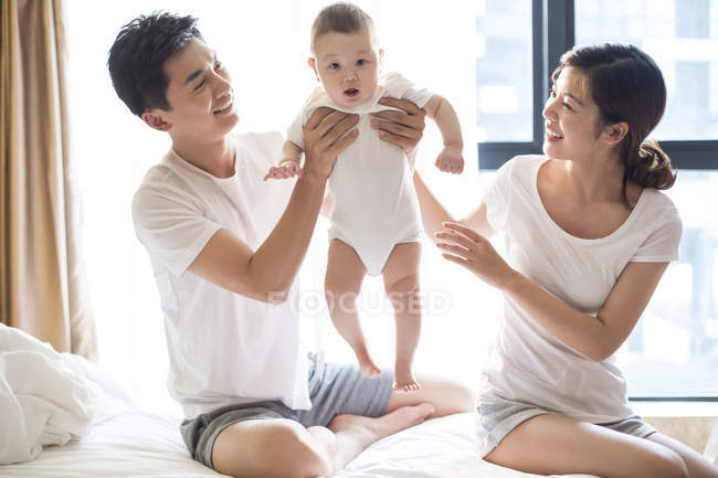 Chinesischer Vater und Mutter halten Baby im Bett — Stockfoto