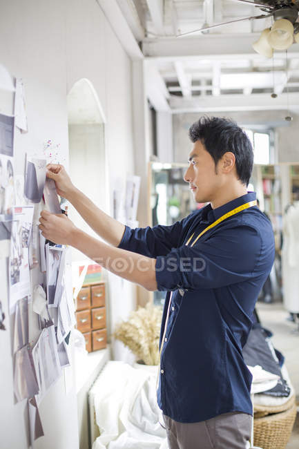 Designer de moda chinesa pinning esboços na parede do estúdio — Fotografia de Stock