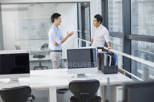 Китайские бизнесмены разговаривают в офисном интерьере — стоковое фото