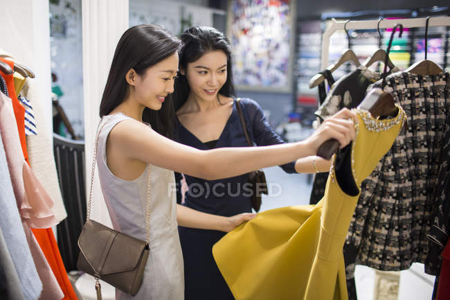 Chinesische Freundinnen betrachten Kleid im Bekleidungsgeschäft — Stockfoto