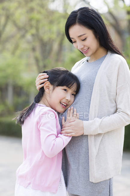 Asiatique fille écoute enceinte mère ventre — Photo de stock