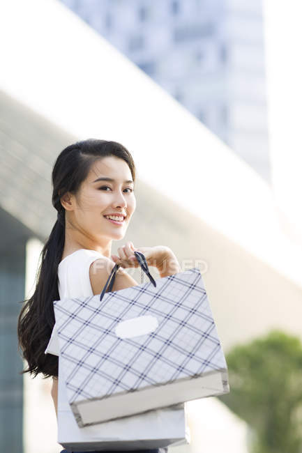 Mulher asiática posando na rua com sacos de compras — Fotografia de Stock
