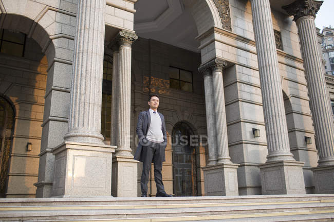 Chinese businessman standing on building staircase in city — Stock Photo