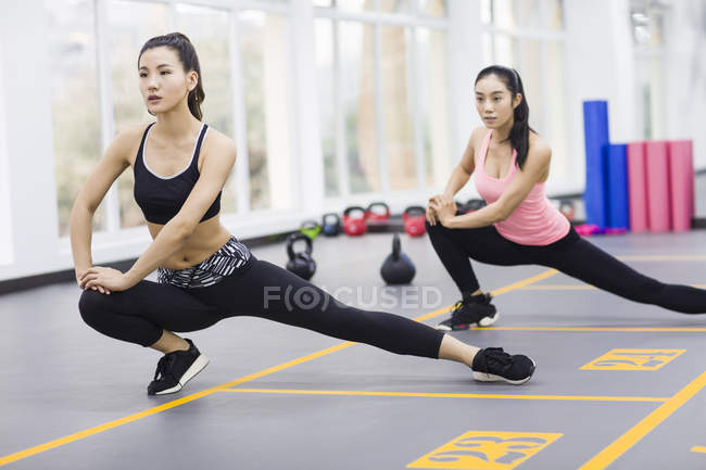 Asiático mujeres estiramiento en gimnasio - foto de stock