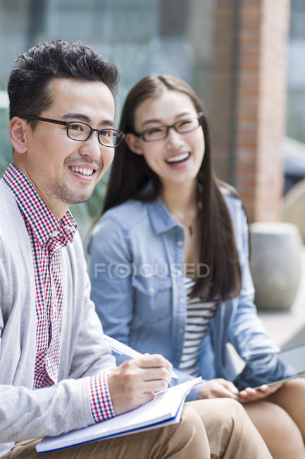 Азиатский мужчина и женщина улыбаются и смотрят вдаль на улице — стоковое фото