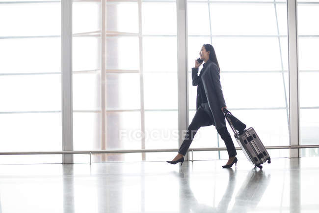 Mulher asiática andando e falando ao telefone no aeroporto — Fotografia de Stock