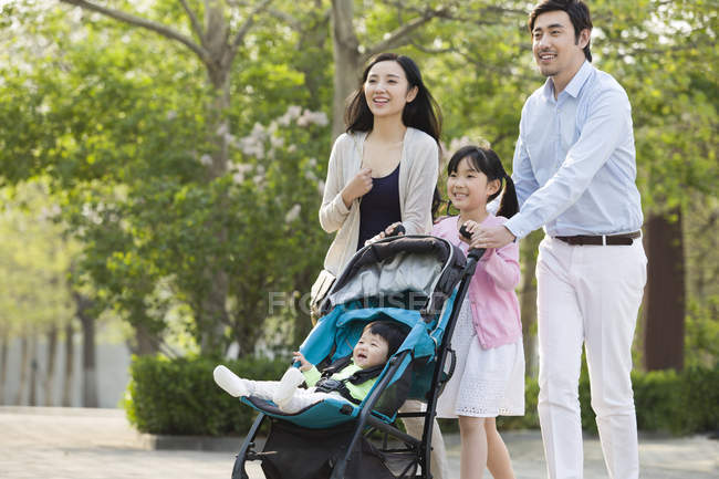 Asiática familia caminando con bebé en parque - foto de stock