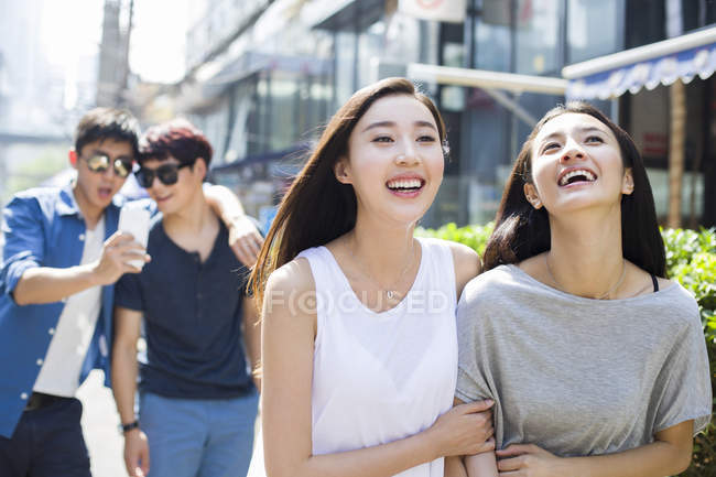 Amici femminili cinesi che camminano con gli uomini sulla strada — Foto stock