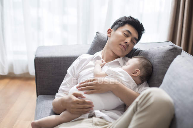 Chinese father and baby boy sleeping together on sofa — Stock Photo