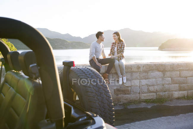 Chinese couple sitting on lakeside in suburbs — Stock Photo