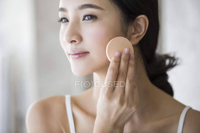 Jovem chinesa aplicando pó facial — Fotografia de Stock