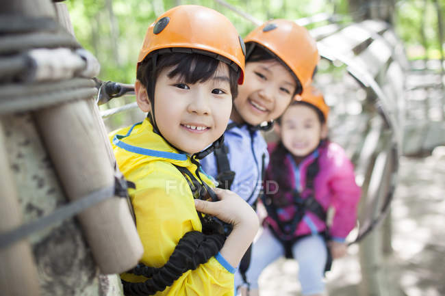 Niños chinos posando en el parque de aventuras árbol superior - foto de stock