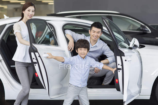 Família chinesa sentada no carro no showroom — Fotografia de Stock