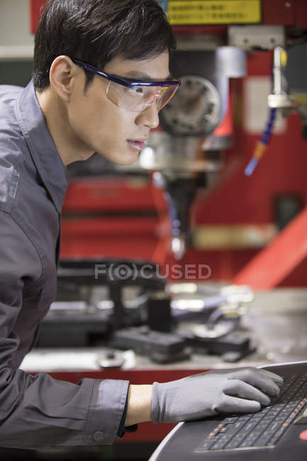 Confident Chinese engineer working with laptop at industrial factory — Stock Photo