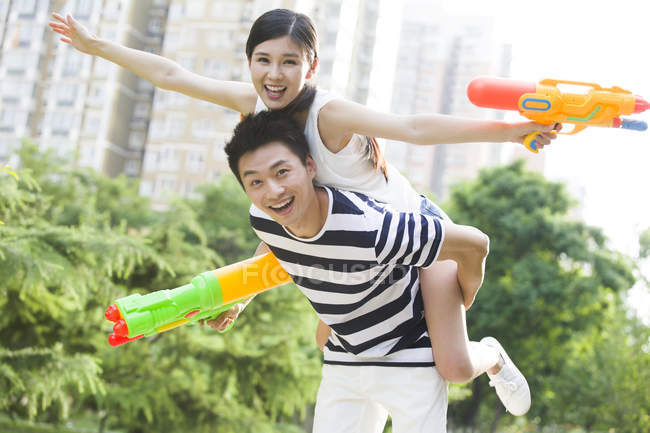 Giovane coppia cinese adulta giocare con pistole a spruzzo — Foto stock