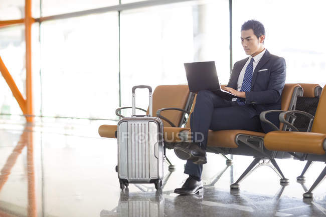 Homme d'affaires chinois utilisant un ordinateur portable dans la salle d'attente de l'aéroport — Photo de stock