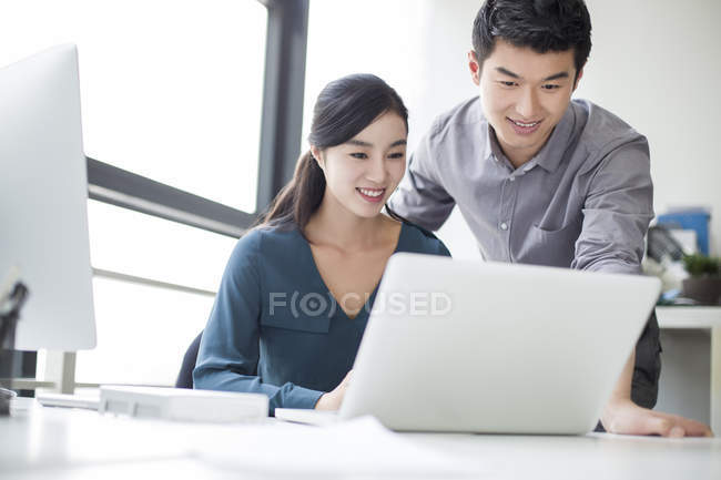 Chinese co-workers using laptop in office — Stock Photo