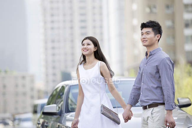 Chinesisches Paar hält Hand vor Auto — Stockfoto