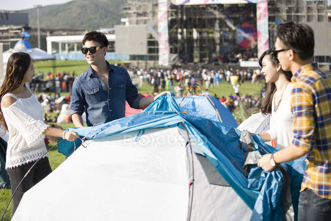 Китайские друзья устанавливают палатку на фестивальной лужайке — стоковое фото