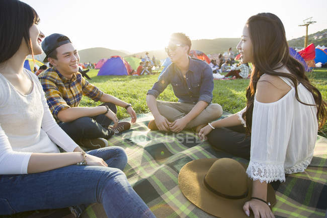 Amigos chinos sentados en manta en el festival de música - foto de stock