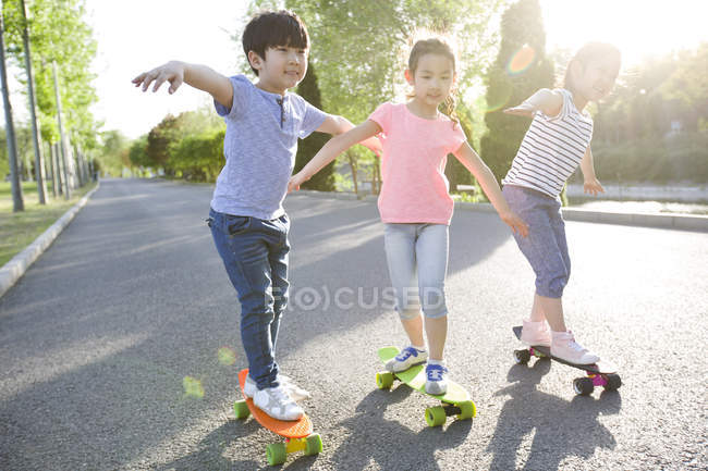 Chinese children skateboarding on park road — Stock Photo