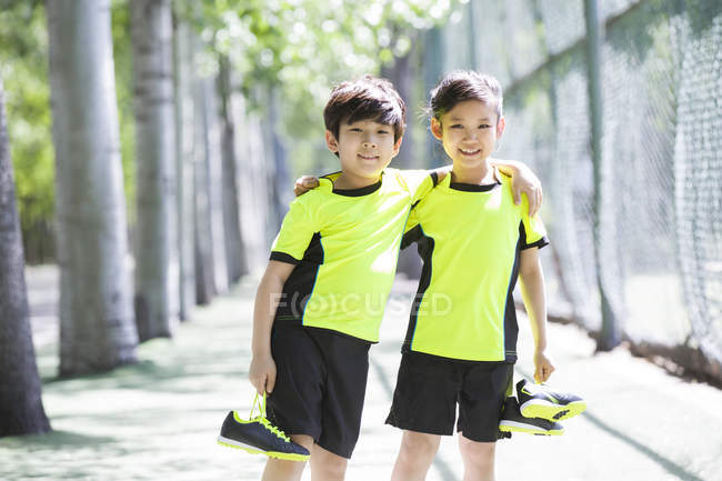 Niños chinos en ropa deportiva de pie en el parque - foto de stock