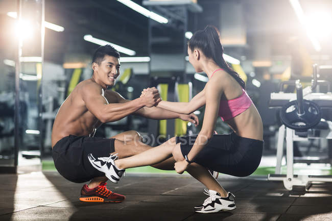 Chinese couple doing sit ups together at gym — Stock Photo