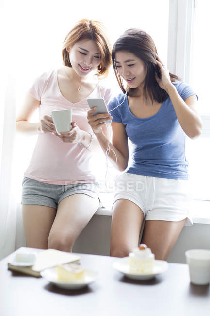 Жінки друзі слухають музику вдома — стокове фото