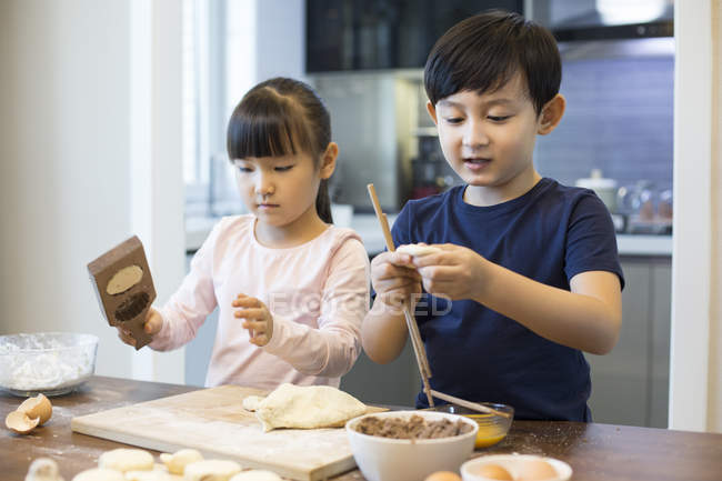 Irmãos chineses fazendo bolinhos de massa na cozinha — Fotografia de Stock