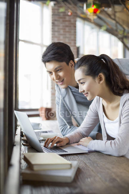 Китаец и женщина используют ноутбук в кафе — стоковое фото
