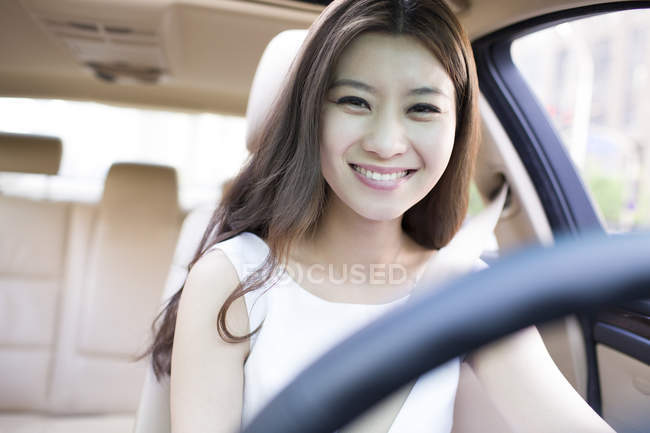 Улыбающаяся китаянка за рулем машины — стоковое фото