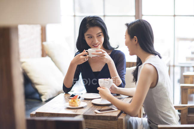 Chinois amies boire du café et parler dans le café — Photo de stock