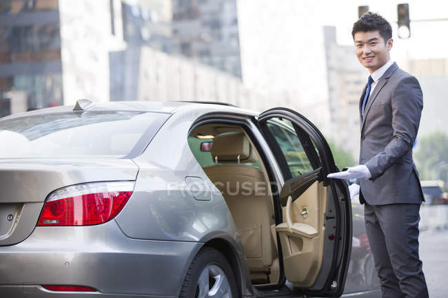 Китайський шофер відчиняє двері машини. — стокове фото