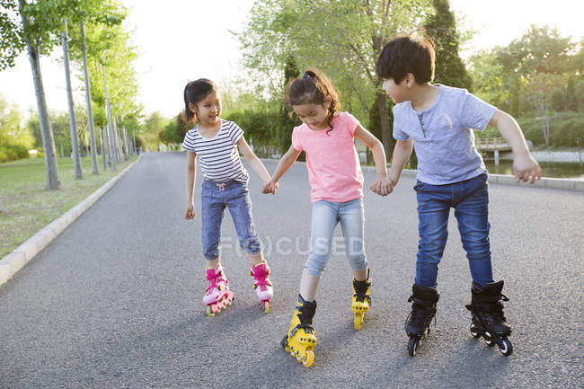 Bambini cinesi pattinaggio a rotelle su strada parco — Foto stock