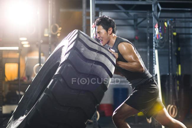 Chinois poussant gros pneu dans Crossfit gym — Photo de stock