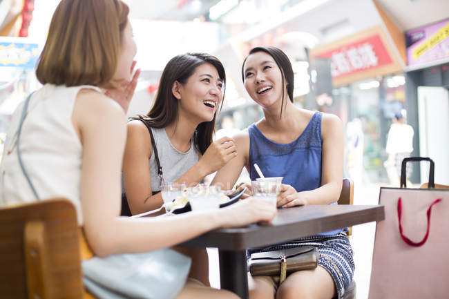 Female friends laughing at sidewalk cafe — Stock Photo