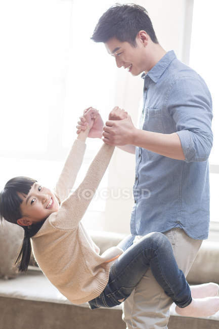 Asiatischer Vater hält Tochter im Wohnzimmer — Stockfoto