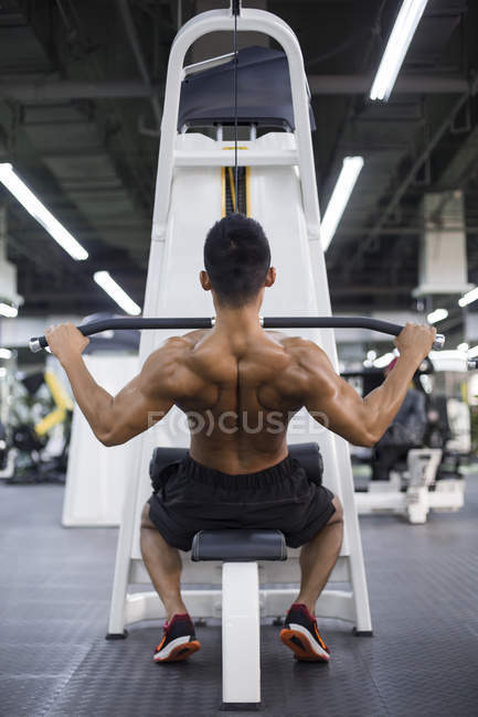 Young man exercising at gym equipment — Stock Photo